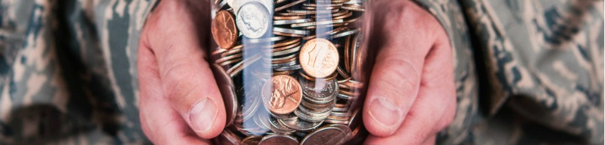 US military serviceman holding jar full of coins @istockphoto.com/Catherine Lane