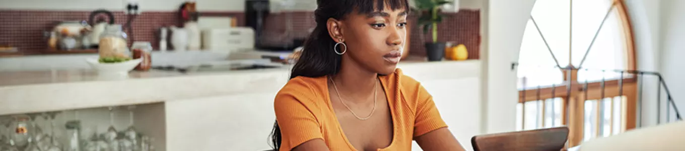 Young Woman Focused on Laptop and Paperwork at Home